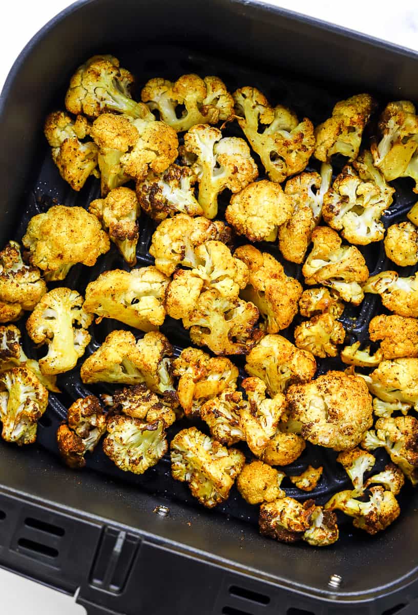 Golden, crispy cauliflower in a black air fryer basket.